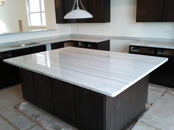 A large kitchen island with white marble counter tops.