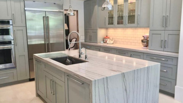 A kitchen with marble counter tops and white cabinets.