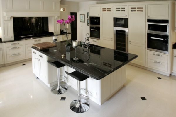 A kitchen with black and white counters, and a large island.
