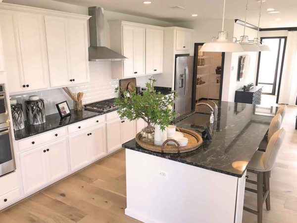 A kitchen with white cabinets and black granite counter tops.