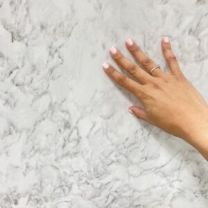 A person 's hand on the counter of a marble countertop.