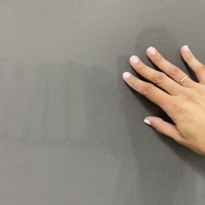 A hand is touching the wall with their fingers.