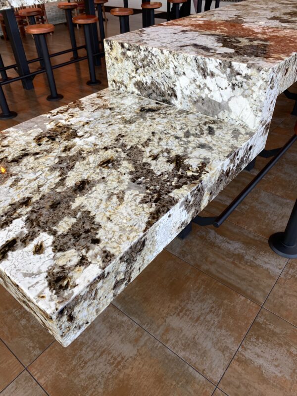 A marble bench with brown and white spots on it.